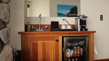 Una encimera de madera con una cafetera y un refrigerador lleno de bebidas.