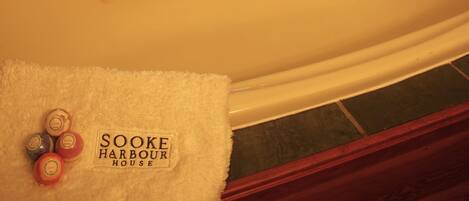 A bathroom with a white bathtub, a window with a view of the outside, and a towel with the text "SOKE HARBOUR HOUSE".