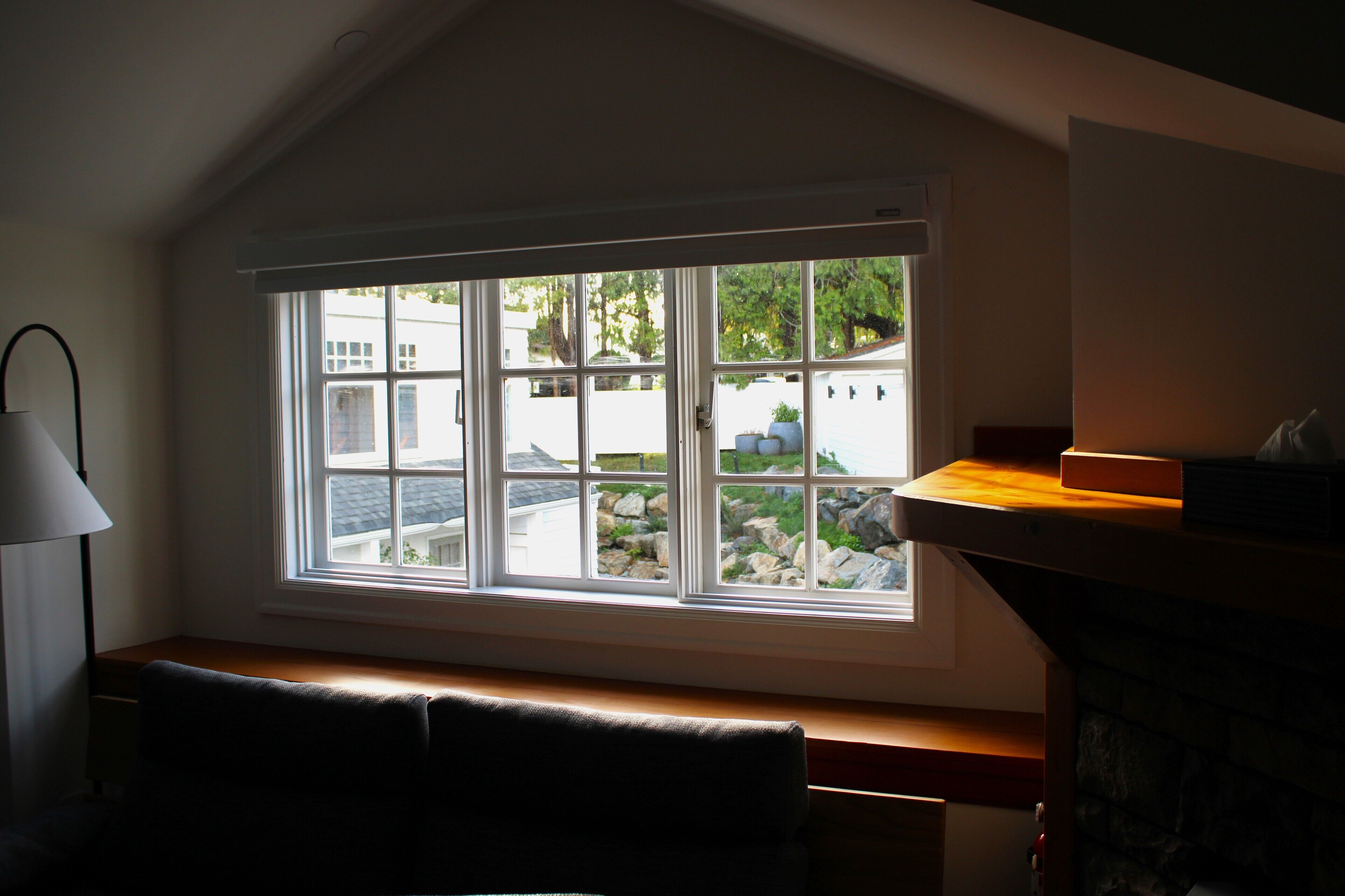A room with a large window, a bench, and a fireplace.