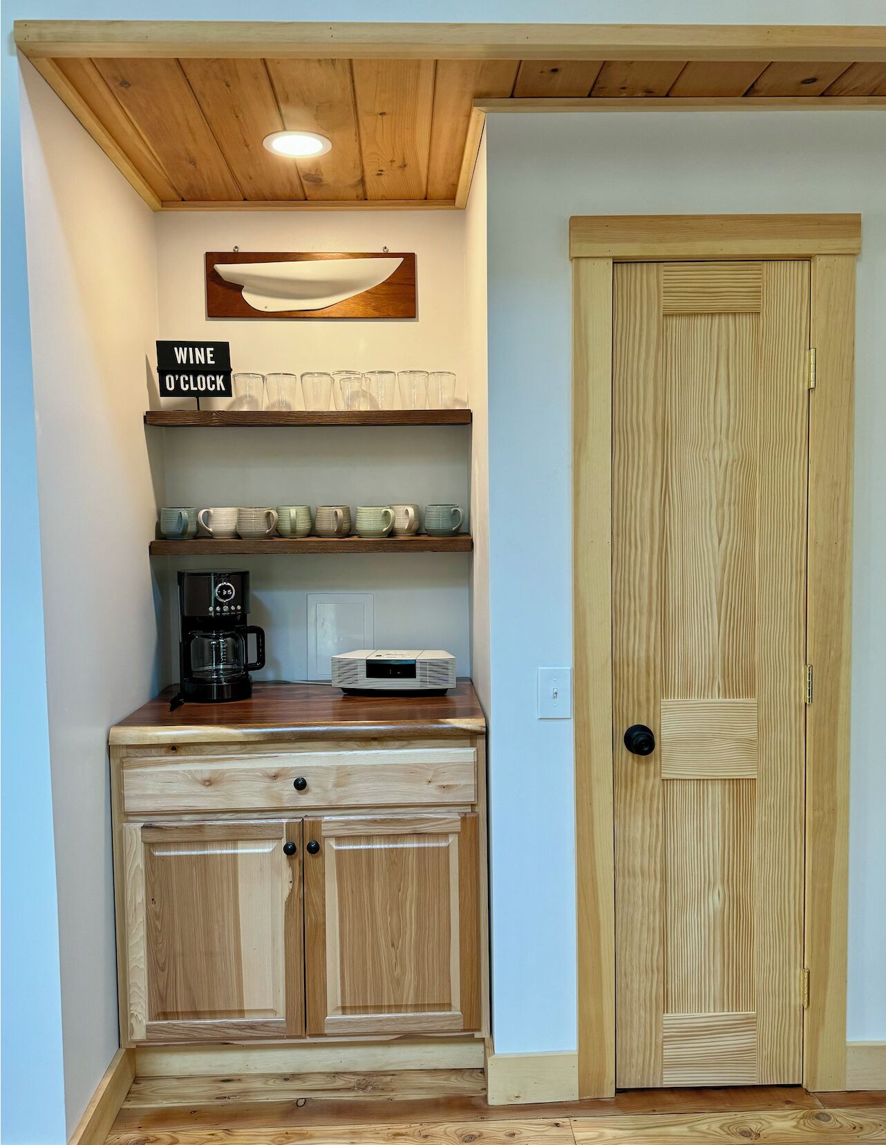 Una cucina compatta con mobili in legno, una macchina da caffè e un cartello che invita a degustare il vino.