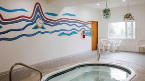 A swimming pool with a tiled floor, a wall mural with wavy lines, and a fire extinguisher. - On Hill Mountain Retreat (Kimberley)