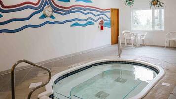 A swimming pool with a tiled floor, a wall mural with wavy lines, and a fire extinguisher.
