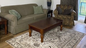 A living room with a sofa, a patterned rug, a coffee table, a lamp, a chair, and a painting on the wall. - On Hill Mountain Retreat (Kimberley)