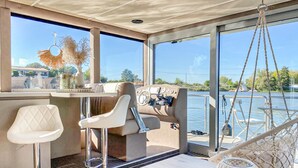 L'intérieur d'un bateau est aménagé avec un espace salon doté de sièges rembourrés, un panneau de commande et de grandes fenêtres offrant une vue sur l'eau.