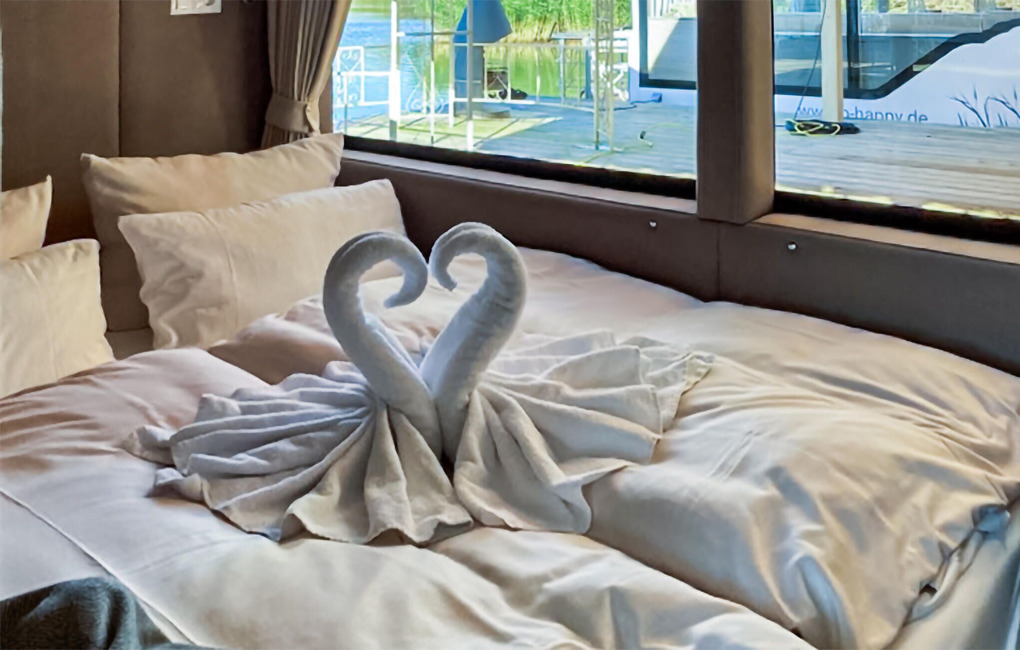 Una cama con una toalla dispuesta en forma de corazón.