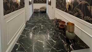 A hallway with patterned wallpaper, marble flooring, and wall sconces. - Lovely rooms (La Spezia)