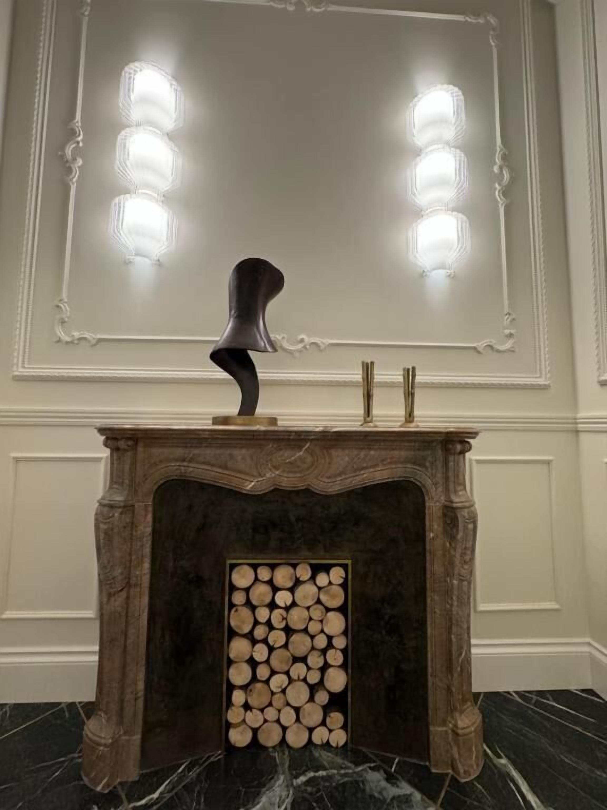 Una chimenea de mármol con un fuste decorativo y un leñero.