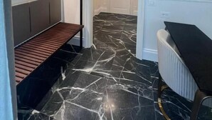 A hallway with a marble floor, a bench, a radiator, and a door leading to another room. - Lovely rooms (La Spezia)