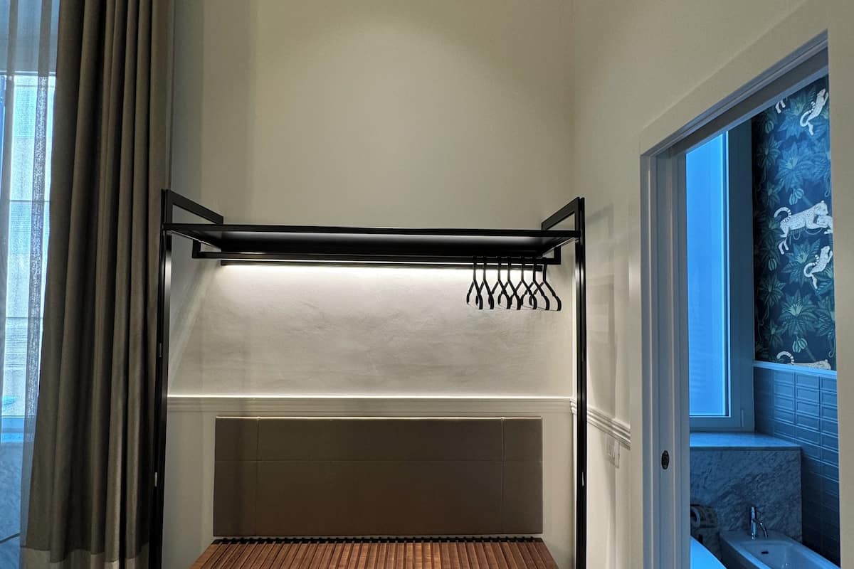 Habitación pequeña con una cama litera, un banco de madera, piso de mármol y vistas al baño con bañera.
