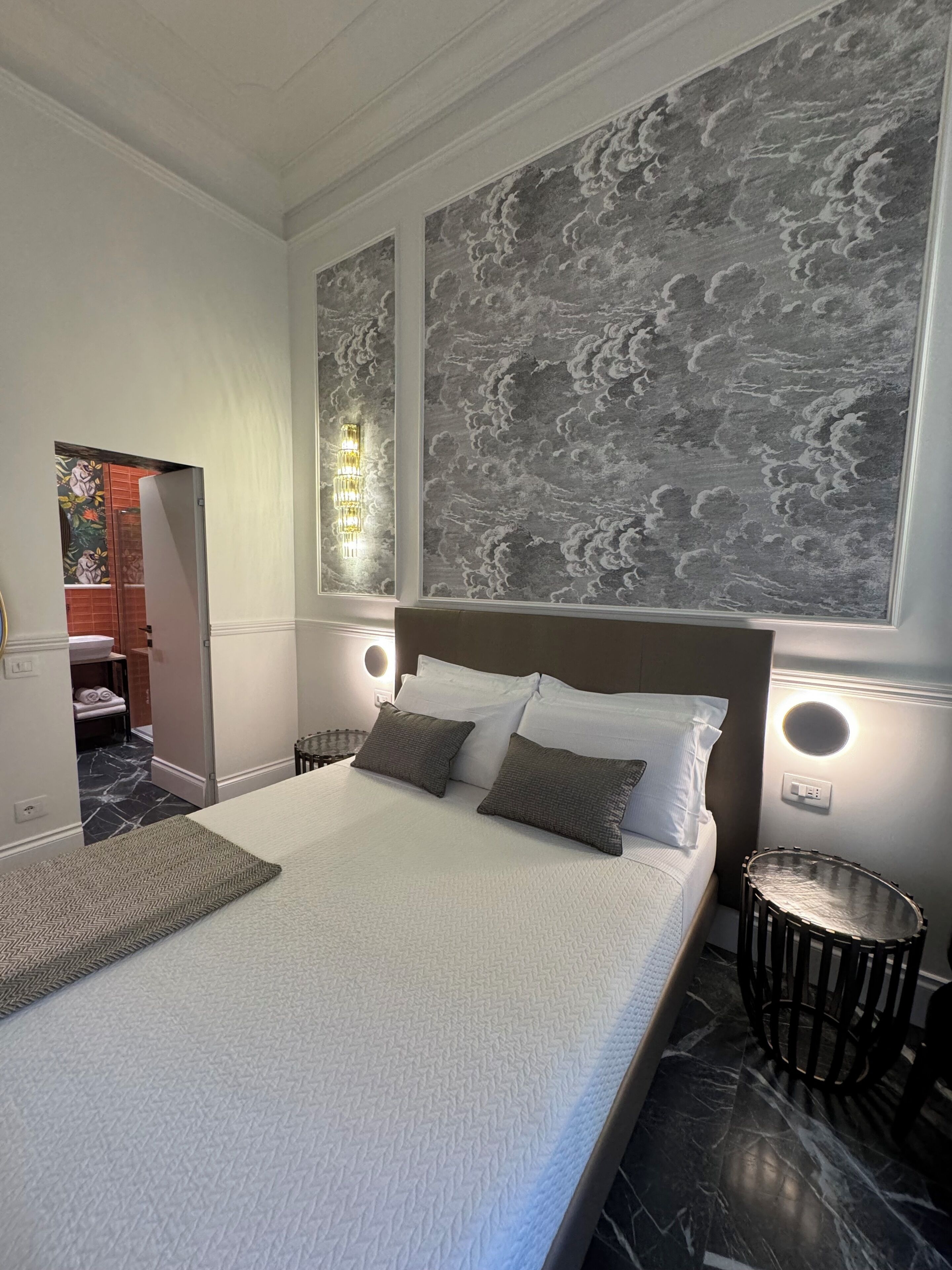 Un dormitorio moderno con una cama grande, suelo de mármol y una pared con diseño de nubes.