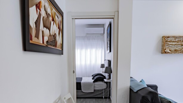 A modern living room with a black sofa, white chairs, and a framed picture on the wall. - Baya Azul Bayahibe - Apto 204 (San Rafael del Yuma)
