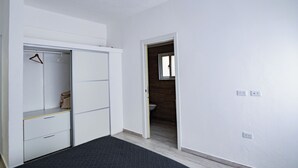 A room with a wardrobe, a small closet, and a doorway leading to a bathroom. - Baya Azul Bayahibe - Apto 204 (San Rafael del Yuma)