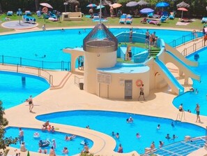 A large outdoor swimming pool with multiple lanes and a central water slide. - Modern Studio Sea Views in Benalmádena - Available for weekly or monthly rentals (Benalmádena)