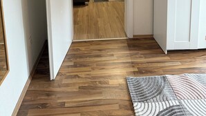 A hallway with a wooden floor leading to a room with a bed and a lamp. - Be Home in Dortmund (Dortmund)