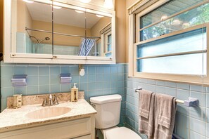 Een badkamer met een wastafel, toilet en een raam.