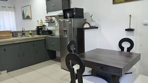 Eine kleine Küche mit Esstisch und Stühlen, einer Mikrowelle und einem Kühlschrank.