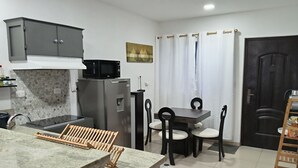 Eine kleine Küche mit Mikrowelle, Kühlschrank und einem Essbereich mit Stühlen und Tisch.
