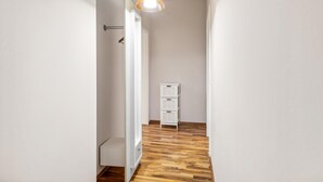 A narrow hallway with wooden flooring, white walls, and a white storage unit against the wall. - 1 bedroom lovely apartment in Anklam (Anklam)