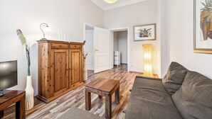 A living room with a wooden cabinet, a sofa, a TV, and a lamp. - 1 bedroom lovely apartment in Anklam (Anklam)
