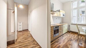 A modern kitchen with wooden flooring, white cabinets, and a built-in oven. - 1 bedroom lovely apartment in Anklam (Anklam)