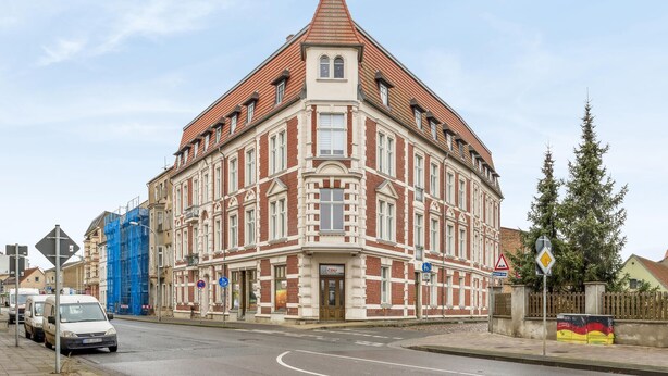 A corner building with a red-tiled roof, multiple windows, and a visible entrance. - 1 bedroom lovely apartment in Anklam (Anklam)