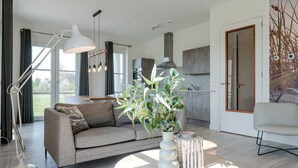 Una sala moderna con un sofá gris, una lámpara de pie blanca y una mesa de centro redonda con una planta.