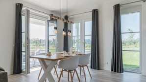 Un comedor moderno con una mesa de madera, sillas blancas y una lámpara colgante.