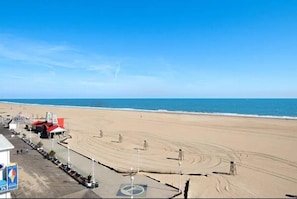 Ein Strand mit Promenadenweg, Rettungstürmen und einem Gebäude mit rotem Dach.