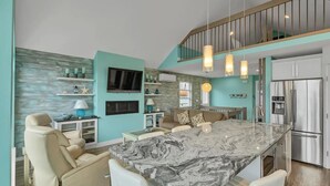 A modern kitchen with a marble island, stainless steel appliances, and a cozy seating area with a view of the outdoors. - La Casa Cottage Beach Vibe, Entire Home Lake Views (Kelowna)