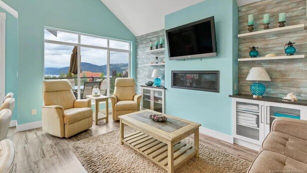 A living room with a large window, a flat-screen TV, and a wooden coffee table. - La Casa Cottage Beach Vibe, Entire Home Lake Views (Kelowna)