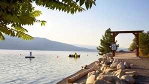 A lakeside walkway with a wooden pergola and a signpost. - La Casa Cottage Beach Vibe, Entire Home Lake Views (Kelowna)