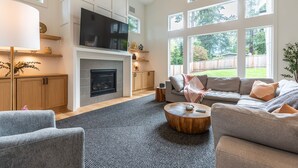 A spacious living room with a fireplace, a large TV, and a comfortable seating area with a sofa and chairs. - Bellevue Dream w/ Spacious 6BR Luxury Home (Bellevue)