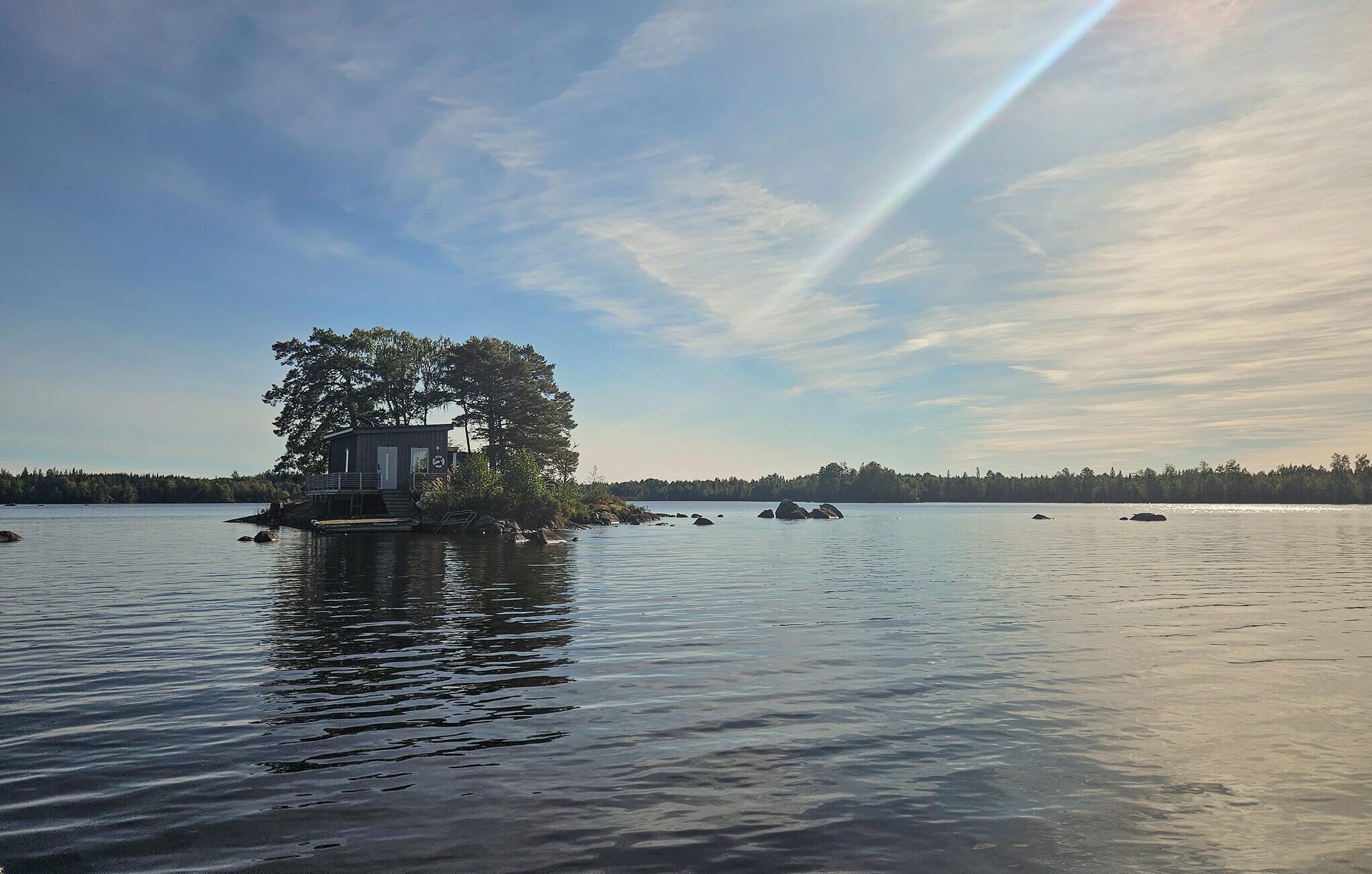 Eine kleine Holzhütte an einem See, umgeben von Bäumen.