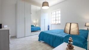 Ein Schlafzimmer mit Bett, Nachttischlampe, Spiegel und Fenster.