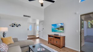A modern living room with a sofa, coffee table, TV, and wooden cabinet. - City Center Townhouse with Private Yard! (Tucson)
