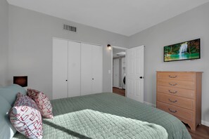 Un dormitorio con cama, cómoda, un cuadro y una puerta que da a otra habitación.
