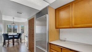 A modern kitchen with wooden cabinets, a stainless steel refrigerator, and a dining area with a table and chairs. - City Center Townhouse with Private Yard! (Tucson)