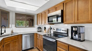 A modern kitchen with wooden cabinets, stainless steel appliances, and a large window providing natural light. - City Center Townhouse with Private Yard! (Tucson)