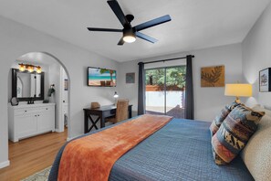 A bedroom with a bed, a desk, a chair, a ceiling fan, a window with curtains, and artwork on the walls. - City Center Townhouse with Private Yard! (Tucson)
