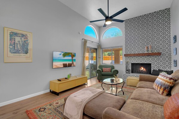 A living room with a fireplace, a television, and a green armchair.