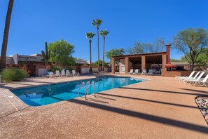 Une piscine à l’eau d’un bleu cristallin, entourée de chaises longues et d’un espace de détente abrité.