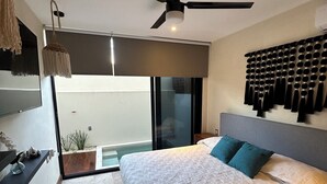 A modern bedroom with a large bed, a ceiling fan, a sliding glass door to a balcony, and a wall-mounted towel rack. - HEAVENLY MAYAN ESCAPE CHIC 1 BDRM APT 250 MB WiFi IN HEART OF TULUM, PLUNGE POOL (Tulum)