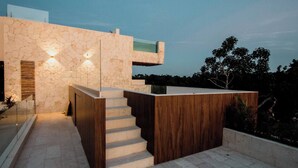 A modern outdoor staircase leading to a wooden deck with a stone wall backdrop. - HEAVENLY MAYAN ESCAPE CHIC 1 BDRM APT 250 MB WiFi IN HEART OF TULUM, PLUNGE POOL (Tulum)