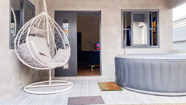 Ein Zimmer mit einer Hängematte, einer Whirlwanne und einer Tür zu einem weiteren Raum.