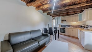 A modern kitchen with wooden beams, a dining area with a black leather sofa, and a white table. - Lovely home in Mont-Dol with WiFi (Mont-Dol)
