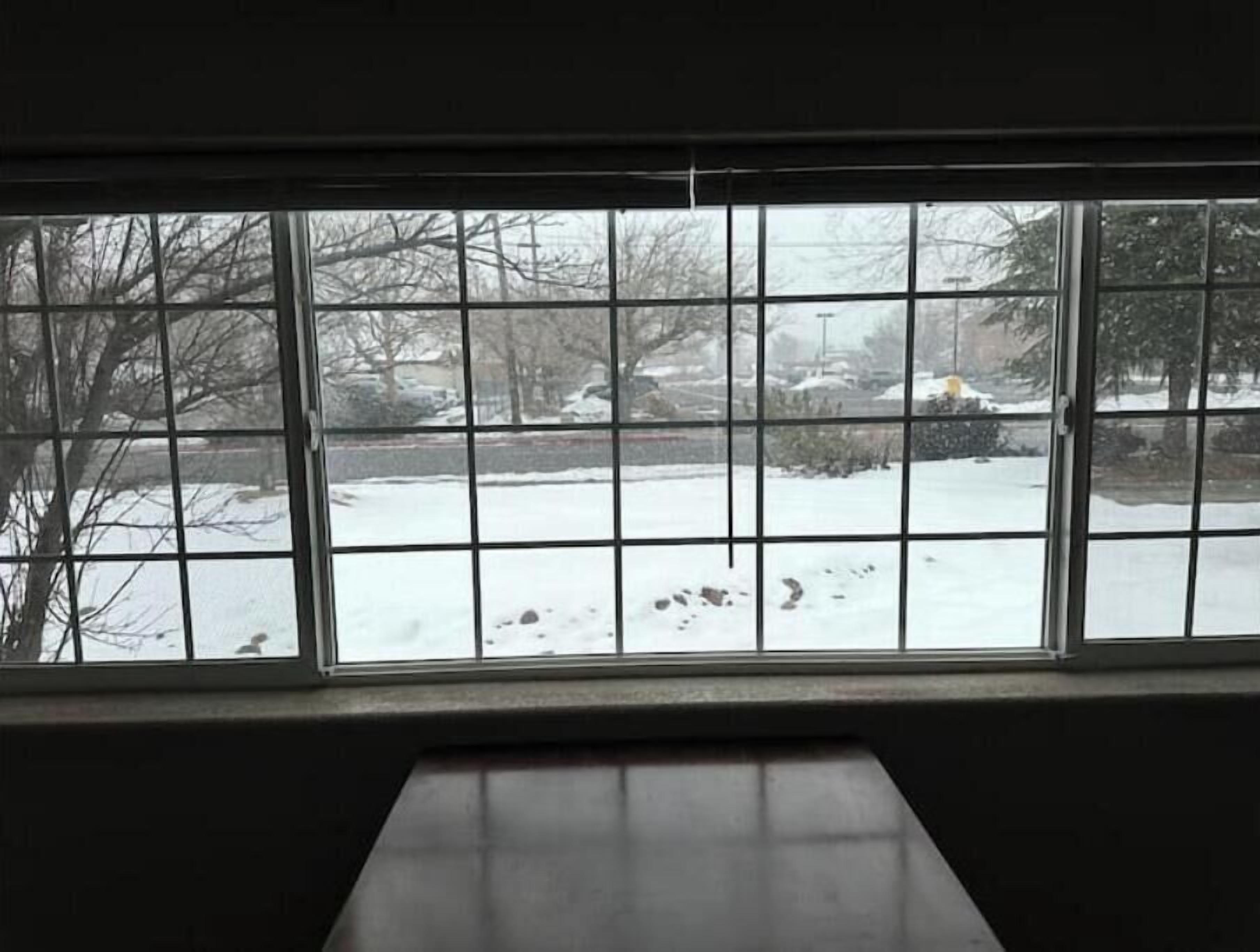 Ein Zimmer mit einem großen Fenster mit Blick auf eine verschneite Landschaft.