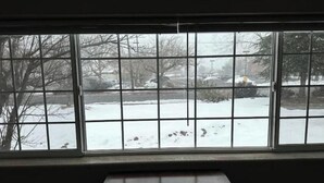 Ein Zimmer mit einem großen Fenster mit Blick auf eine verschneite Landschaft.