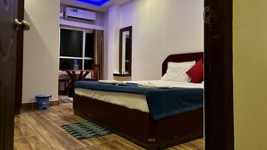 Ein Hotelzimmer mit Bett, Schreibtisch, Stuhl, Fenster und Klimaanlage.
