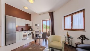 A modern kitchen with a refrigerator, oven, and microwave. There is a dining area with a table and chairs. A sofa and a glass coffee table are also visible. - Lovely apartment in Pula with WiFi (Pula)