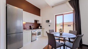 A modern kitchen with a stainless steel refrigerator, white cabinets, a microwave, and a dining area with a round table and chairs. - Lovely apartment in Pula with WiFi (Pula)